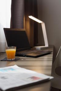 福利尼奥City Hotel & Suites的坐在带笔记本电脑的书桌上,喝一杯橙汁