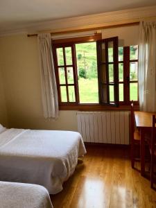 桑提亚纳德玛Posada Adela的一间卧室设有两张床、一张桌子和窗户。