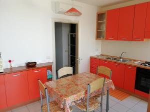 圣卡特琳娜迪纳德La Scogliera的厨房配有红色橱柜和桌椅