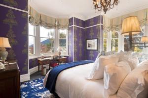 皇后镇Hulbert House Luxury Boutique Lodge Queenstown的一间卧室设有紫色的墙壁和一张带白色枕头的床