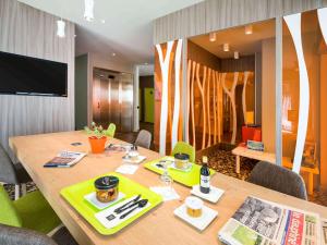 安姆比利Ibis Styles Annemasse Genève的一间带木桌和电视的用餐室
