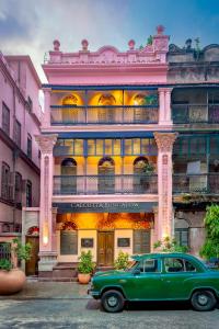加尔各答Calcutta Bungalow的停在大楼前的一辆旧绿色汽车