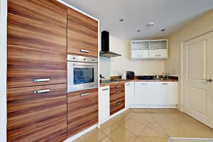 法恩伯勒Blue Sky Apartments @Wallis Square, Farnborough的厨房配有白色橱柜和木镶板