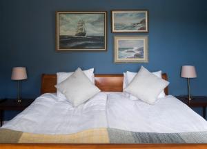 古斯塔堡布洛姆巴拉酒店的卧室配有一张白色床,墙上挂有三张照片