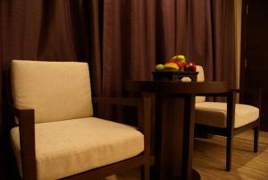 乌隆他尼班雅度假酒店 的一间房间,配有两把椅子和一张桌子及一碗水果