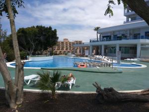 帕莱索海滩Studio Playa Paraiso Tenerife - ocean view and internet wifi optical fiber - for rent的游泳池,有人坐在大楼前的椅子上