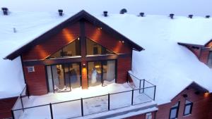 三河城Kinipi Spa Nordique & Hebergement的雪中的房子,灯亮