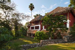 埃尔莱马特Camino Real Tikal‎的红色和白色的房子,带有茅草屋顶