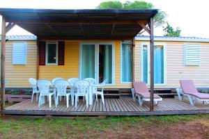 勒米伊Mobil home florida - camping les cigales - 4 étoiles的一个带桌椅的甲板和一座房子