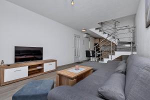 马卡尔斯卡Apartmani R&B Radalj的带沙发和电视的客厅以及楼梯。