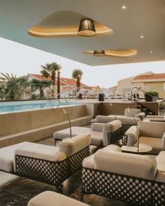 马卡尔斯卡Boutique Hotel Ani - Adults Only的一间带椅子和游泳池的餐厅