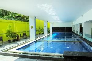 日惹Zest Yogyakarta by Swiss-Belhotel International的一座大型游泳池,位于一座拥有黄色墙壁的建筑中