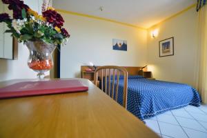 奇斯泰尼诺绿宝石酒店的一间卧室配有桌子和花瓶