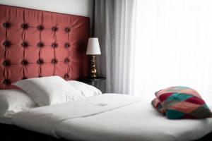 哥德堡弗洛拉酒店的一间卧室配有一张带红色床头板的床和窗户