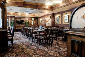 伦敦富勒疯帽子酒店的一间带桌椅和大钟的用餐室