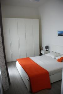 维亚雷焦Casa dolce casa的一间卧室配有一张带白色橱柜和橙色毯子的床。