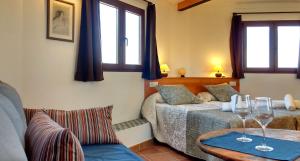 Alhendín科尔蒂霍阿尔盖比亚乡村民宿的一间卧室设有两张床和一张带酒杯的桌子。