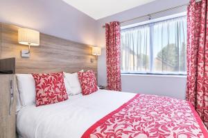 伦敦Hotel Shepherds Bush London的一间卧室配有一张带红色枕头的床和一扇窗户
