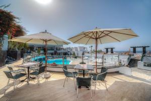 卡门港莫拉纳公寓酒店的游泳池旁带桌子和遮阳伞的天井