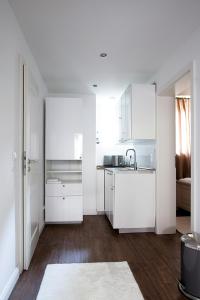 汉堡Ellena`s FEWO am Uke的白色的厨房配有白色橱柜和水槽