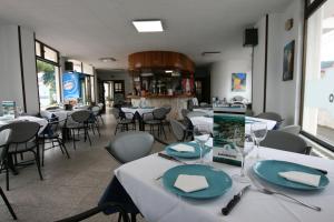 伊斯拉Hotel Candano的一间设有白色桌椅和一张带盘子的桌子的餐厅