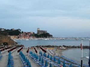 莱里奇Rivamare San Terenzo的一个带椅子和遮阳伞的海滩和一个城堡