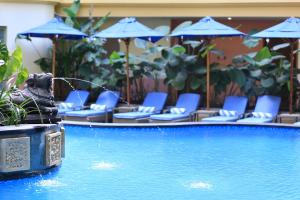 乌布晟诗度假酒店及水疗与会议中心的一个带蓝色椅子和遮阳伞的游泳池