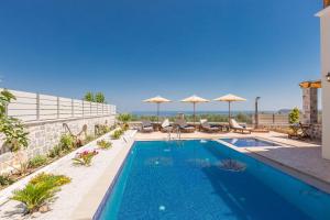 KiriánnaNew Villa Katifes with Pool, Walk to Amenities & Amazing Views!的一座大楼内的游泳池,配有椅子和遮阳伞