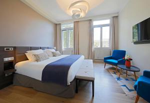 普罗旺斯艾克斯Negrecoste Hôtel & Spa的一间卧室配有一张大床和一张蓝色椅子