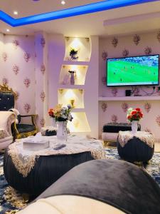 Aţ ŢuwayrBahget Eljouf Furnished Apartment的客厅配有电视和鲜花桌
