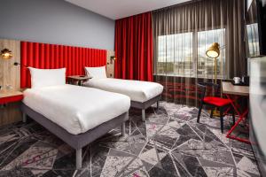 伊灵伦敦伊灵宜必思尚品酒店的配有红色窗帘的酒店客房的两张床