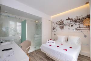 休达德亚Hotel Abril 37的卧室配有带玫瑰花的白色床