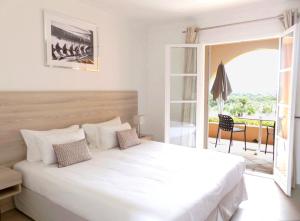 圣特罗佩Hôtel les Bouis - Vue mer的一间带一张白色大床的卧室和一个阳台