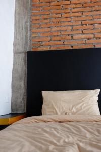 素叻Black Elephant Boutique的一张带黑色床头板和砖墙的床