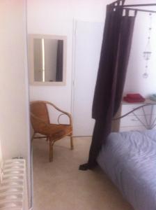 格朗维尔le flibustier的一间卧室配有一张床、一把椅子和镜子