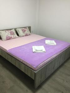 斯塔多伊兰Madzar Apartments的一张大床,上面有紫色的床单和毛巾
