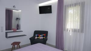 塞沃塔Sivota Colours的卧室配有椅子和墙上的电视