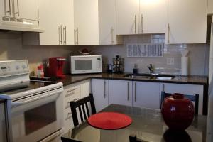 加蒂诺2-Bedroom Apartment #30A by Amazing Property Rentals的厨房配有白色橱柜和红色凳子的桌子
