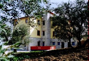 CampodipietraAgriturismo Terra e Sapori的一座黄色和白色的建筑,前面有树木