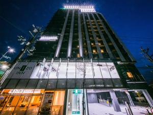 大阪UNIZO INN新大阪旅馆的一座高大的建筑,上面有灯