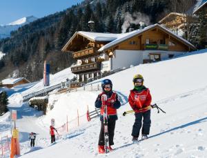 格罗萨尔苏祖特恩霍夫加斯索夫酒店的两人在小屋前的雪地滑雪