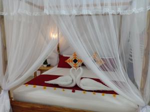 锡吉里亚Victory Villa Sigiriya的一间卧室配有带白色窗帘的床和2条毛巾