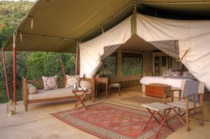 OlolaimutiekEntumoto Main Camp的帐篷配有1张床、1张沙发和椅子