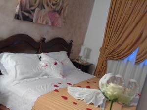 Buttrio卡希纳拉瓦罗尼农家乐的一间卧室配有一张带白色枕头和玫瑰的床。