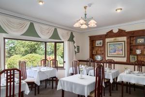基拉尼凯思林乡间别墅酒店的一间设有白色桌椅和窗户的用餐室
