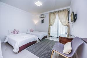 沙敦Bandahara的酒店客房,配有两张床和椅子