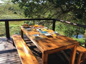 Ponta MalanganeNkumbe Bush Retreat Family Home的甲板上的木桌及酒杯