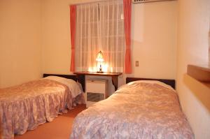 白马村空邮贝提酒店餐厅的一间卧室设有两张床、一个窗口和一张桌子