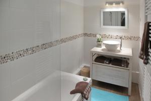 拉波勒La Maison au-dessus des Voiles的白色的浴室设有浴缸和水槽。