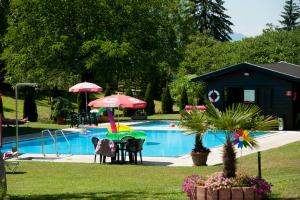 Gödersdorf左纳酒店的一个带桌子和遮阳伞的游泳池以及一座房子
